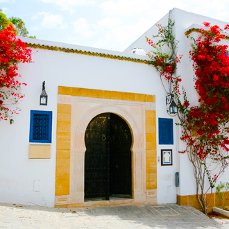 Een kleurrijk gebouw met rode bloemen in Mahdia, Tunesie