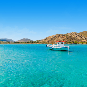Een vissersbootje op helderblauw zeewater op Paros
