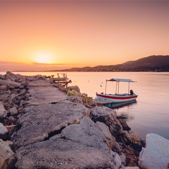 Zonsondergang en een vissersbootje op het Griekse eiland Corfu 