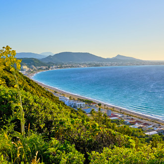 Groene bergen, uitkijkend over de kustlijn met azuurblauwe zee in Ixia 