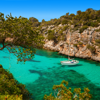 Een kleine jacht op azuurblauwe zee in het dorp Cala Pi op Mallorca