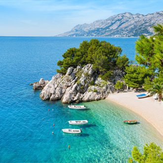 Het strand en helderblauw zeewater met bootjes in Brela, Kroatie