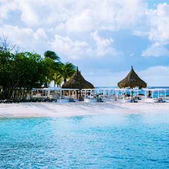 Rieten-parasols-en-strandbedjes-op-het-strand-van-Jan-Thiel-Baai-Curacao