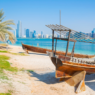 Strand met houten bootjes in de zee en wolkenkrabbers op de achtergrond in Abu Dhabi