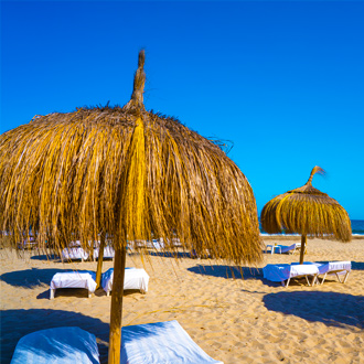 Strand van Playa den Bossa met rieten parasols en ligbedjes
