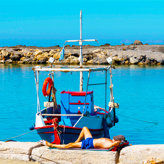 Visserman-doet-een-dutje-naast-zijn-boot-in-de-kleine-haven-van-Gouves-Kreta