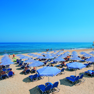 Foto van het strand met ligbedjes en parasols in Adelianos Kampos aan het hotel van Eva Bay
