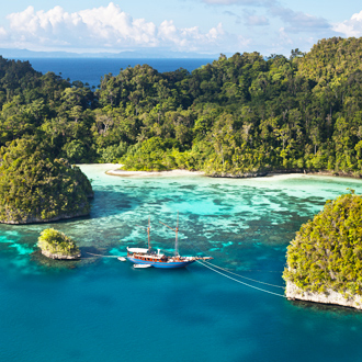 Helderblauwe zee, groene landschap en een vissersboot in Indonesië