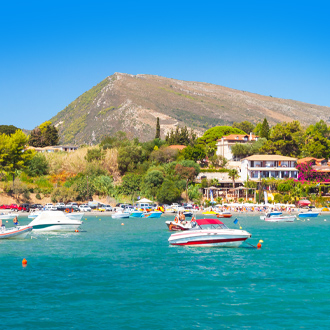 Panorama Agios Sostis met blauwe zee, bootjes en bergen 