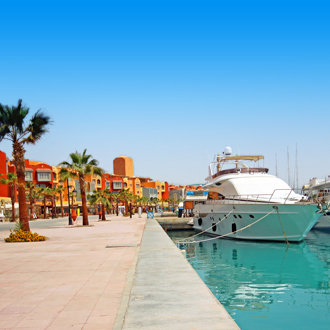 Boulevard met oranje gebouwen, een boot en palmbomen Hurghada