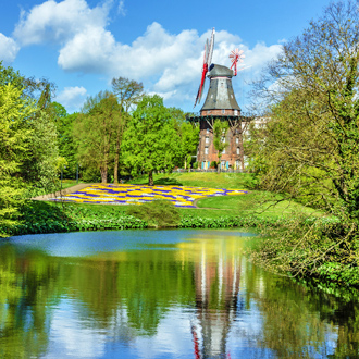 Foto van een molen in een groen park met meer in Bremen
