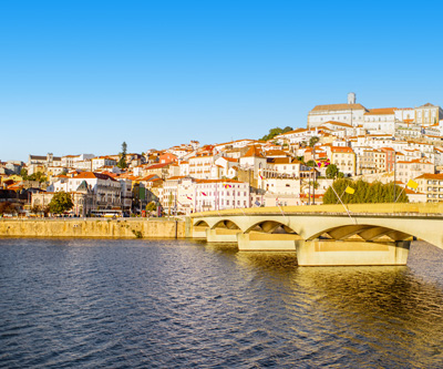 <p>Uitzicht over de stad Coimbra met witte huisjes en brug</p>