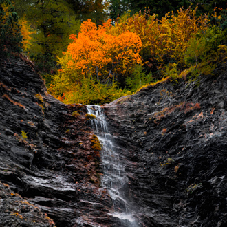 Kleine waterval in de bergen met gekleurde bomen in Crans Montana 