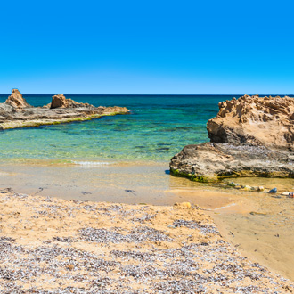 Het wilde strand met helder turquoise water in Malia op Kreta