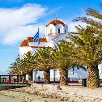 <p>Strand met palmbomen en kerk in Paralia, Griekenland</p>