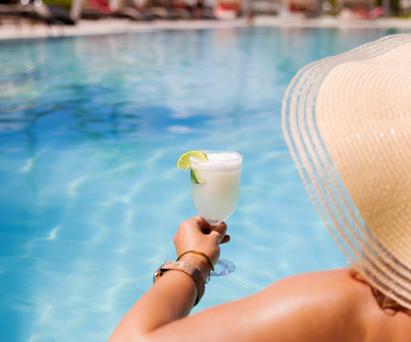 <p>Vrouw met tropisch drankje bij het zwembad op all inclusive vakantie</p>
