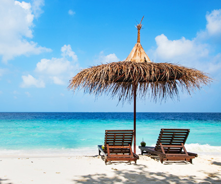 <p>Strandstoelen met rieten parasol bij Piscadera Bay Curacao</p>
