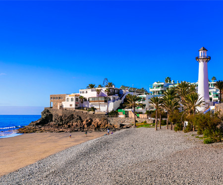 <p>Kiezelstrand en vuurtoren in Bahia Feliz</p>