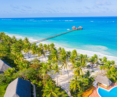 <p>Wit strand, palmbomen en een blauwe zee bij Zanzibar</p>