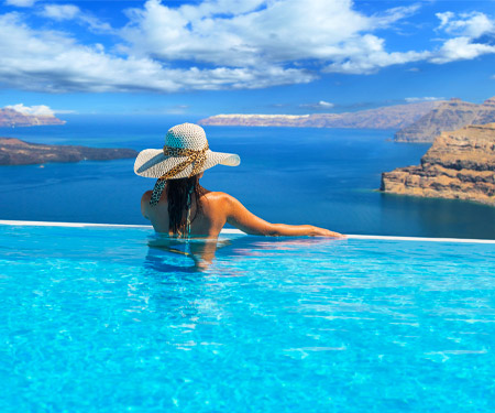 <p>Vrouw met hoed in een luxe infinity pool met uitzicht op zee</p>