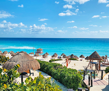<p>Rieten parasols op een wit strand in Cancun, Mexico</p>