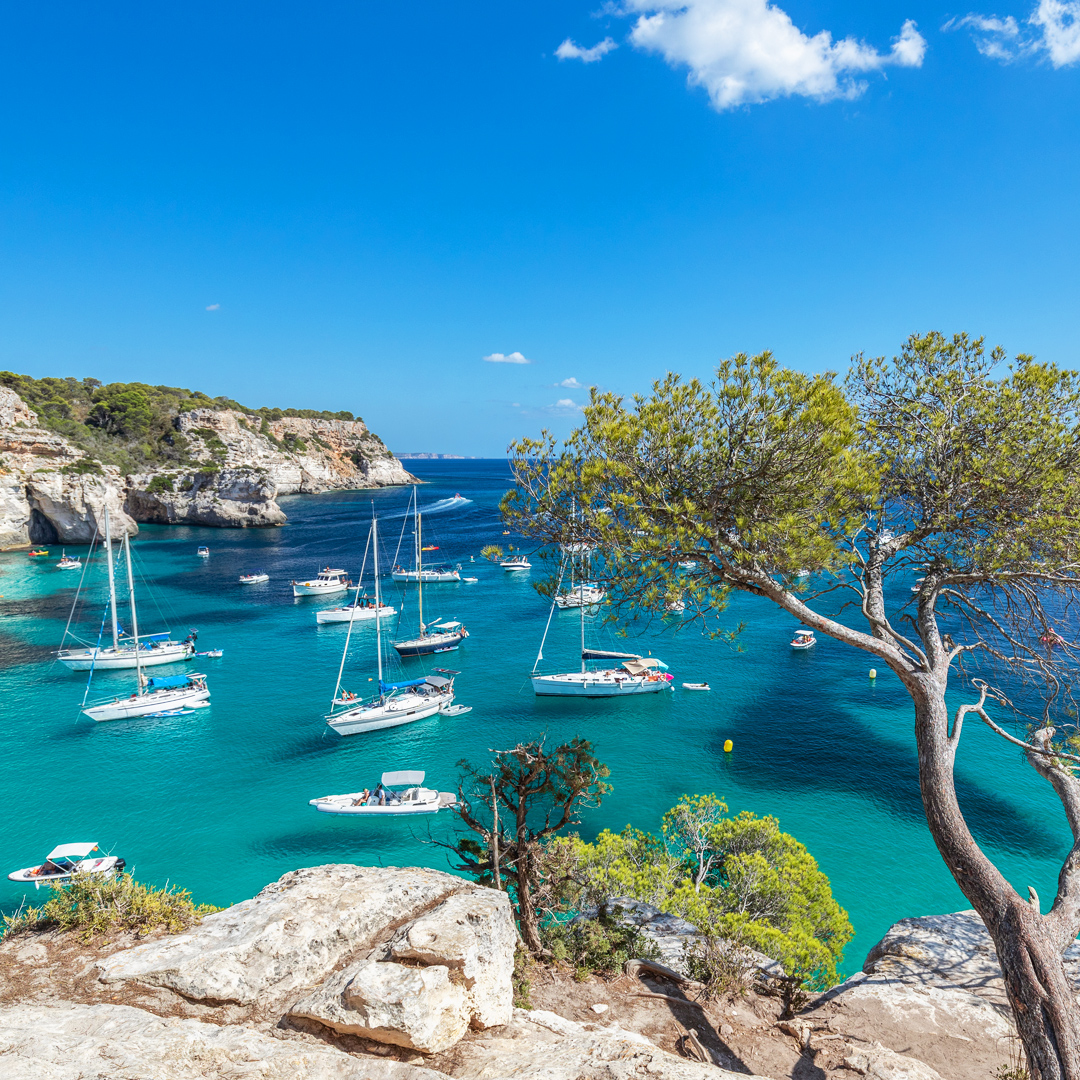 <p>Baai met blauwe zee en bootjes op Menorca</p>