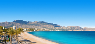 Strand van Albir bij Alicante met palmbomen, boulevard en bergen aan de kust van Spanje