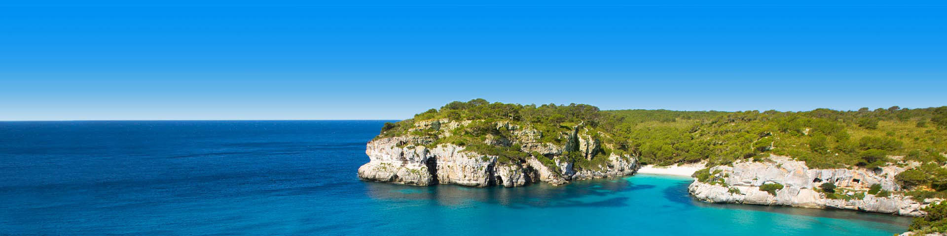 Helderblauwe zee grenzend aan rotsen bij het Spaanse eiland Menorca