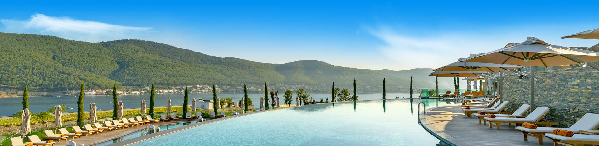Prachtig luxe zwembad met ligbedjes met heuvels en de zee aan de kust van Turkije