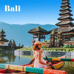 Hangmat hangt aan palmboom op strand in Bali, Indonesië, met blauwe lucht en zee op achtergrond.