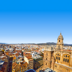 Panorama van Málaga met de kathedraal en rode daken van de stad in zonlicht.