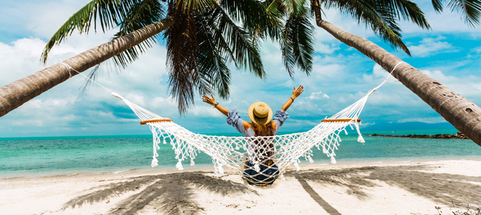 Vrouw in hangmat tussen palmbomen op vakantie