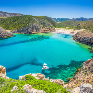 Cala Domestica op Sardinië met goudkleurig strand tussen hoge rotskliffen, helder turquoise water en groene heuvels langs de baai.