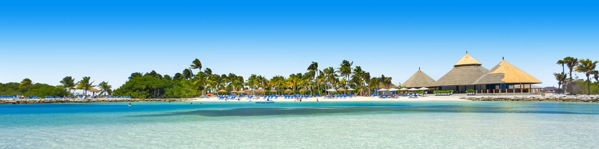 Helderblauwe zee aan de kust van een Caribisch eiland met palbomen en wit zandstrand