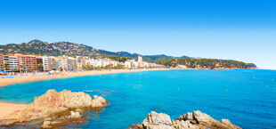 Helderblauwe zee en een zandstrand aan de Costa Brava