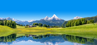 Besneeuwde bergtoppen en groene graslanden in Duitsland, met een weerspiegeling in het water, Duitsland