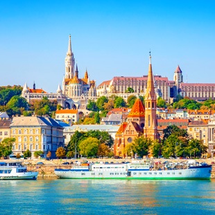 Uitzicht op Boedapest met het parlementsgebouw langs de Donau, bruggen over de rivier en historische architectuur onder een heldere lucht.