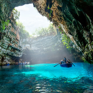 Boottocht op het Melissanimeer, met een roeiboot op helder turquoise water in een grot met invallend daglicht.