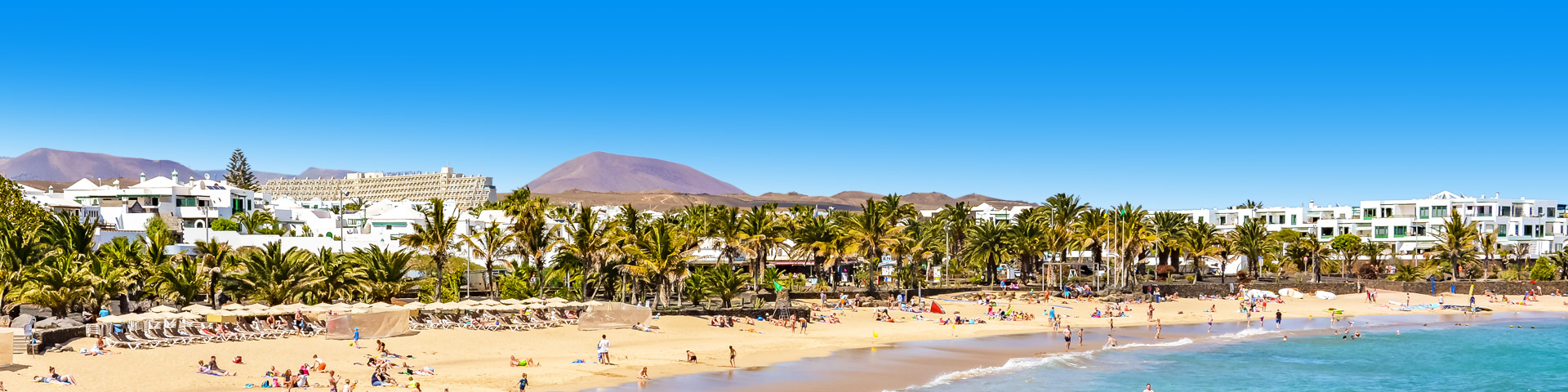 Strand met palmbomen en witte gebouwen Costa Teguise