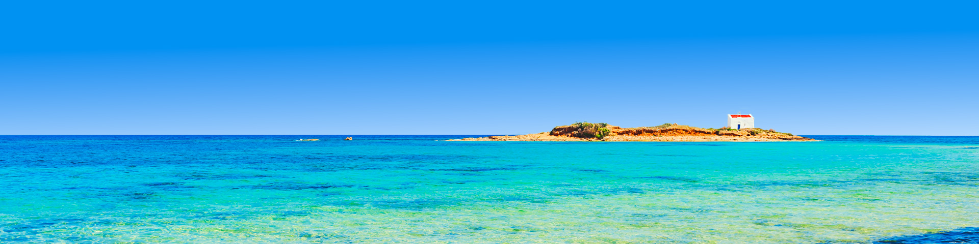 Azuurblauwe zee met eilandje en huisje bij Malia Kreta