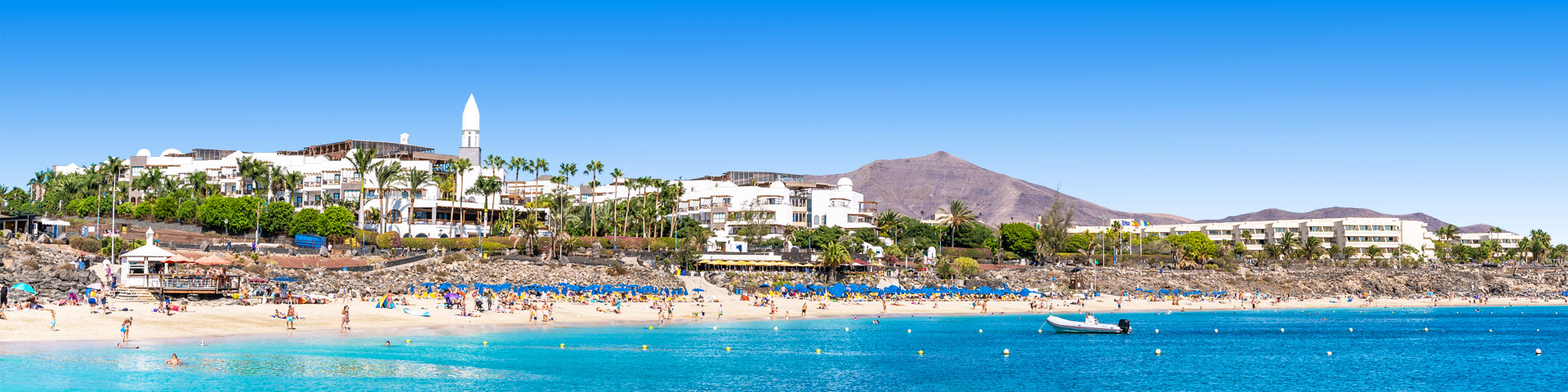Strand met palmbomen en hotels bij Playa Blanca