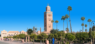 Koutoubia-moskee in Marrakech, Marokko, omringd door palmbomen en blauwe lucht.