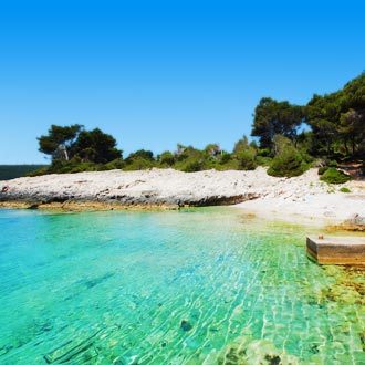 Zicht op Nova Cove in Korčula met helderblauw water, groene bomen en een rustige baai omringd door natuur.