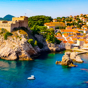 Uitzicht op de oude stad van Dubrovnik met terracotta daken, stadsmuren langs de kust en helderblauw water van de Adriatische Zee.
