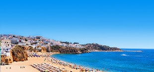 Wit strand met ligbedjes en helderblauwe zee in Portugal