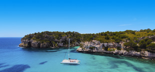 Baai met bootje en helderblauwe zee bij Menorca
