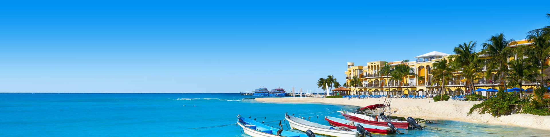 Bootjes in blauwe zee, met uitzicht op een wit strand 