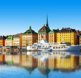 Kleurrijke gebouwen weerspiegelen in het water van Stockholm, Zweden, met boten aan de kade.