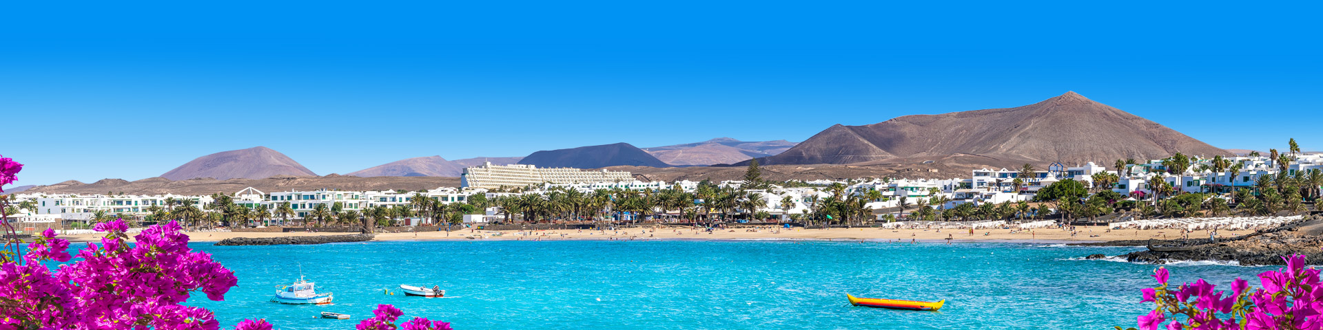 Uitzicht op de kust van Lanzarote met heuvellandschap en witte huisjes aan het strand