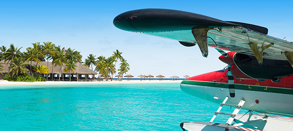 Vliegtuig, helderblauwe zee, palmbomen en een hagelwit zandstrand